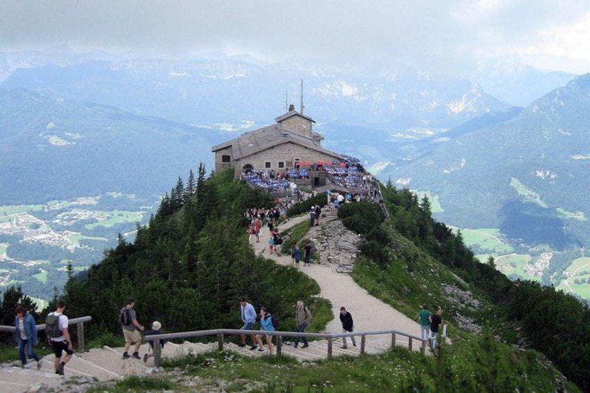 A mountain viewpoint with a building at the top, a path leading up, and a valley below. 3