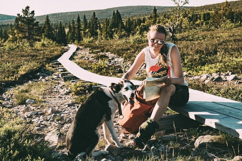 A person sitting on a wooden boardwalk in a natural setting with a dog. 5