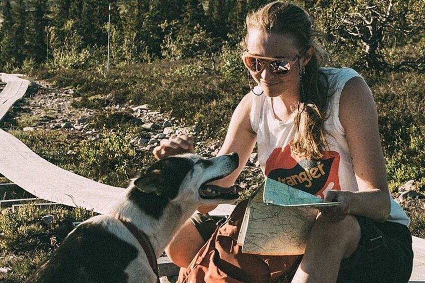 A person sitting outdoors with a dog, holding a map. 3