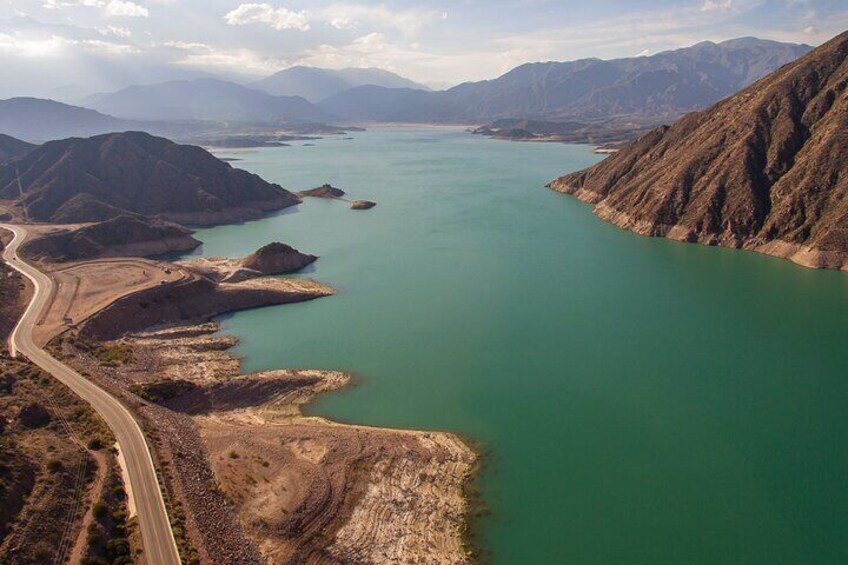 A large body of water surrounded by mountains, a winding road, and a construction site. 2