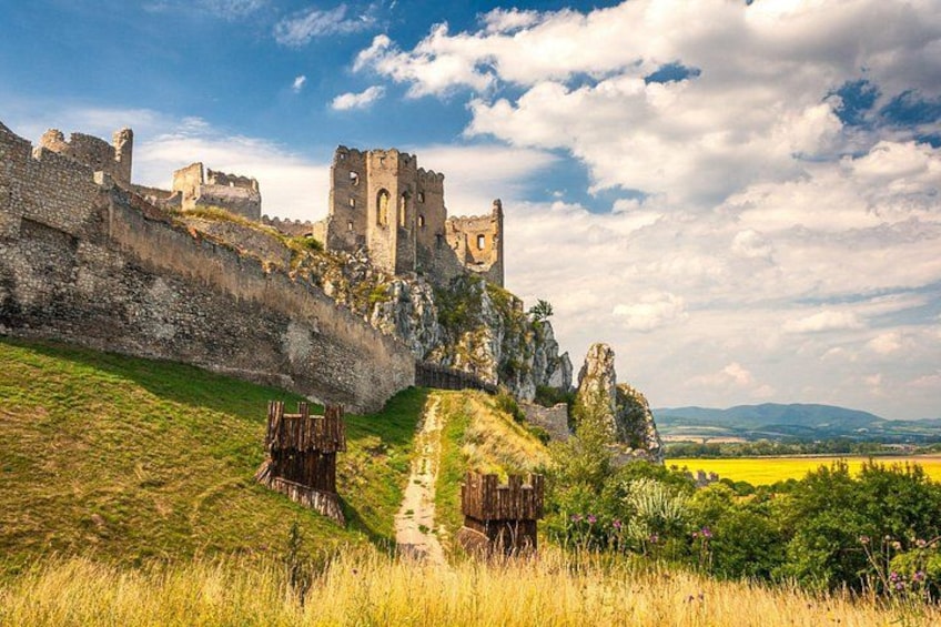 A medieval castle on a hill, surrounded by green fields and a clear sky. 1