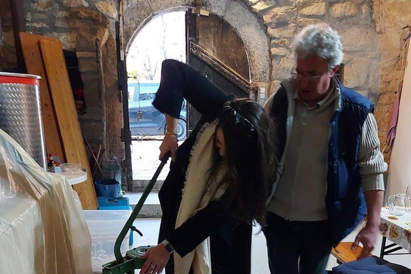 Two people in a rustic stone building, one holding a green hose, another with a tool. 3