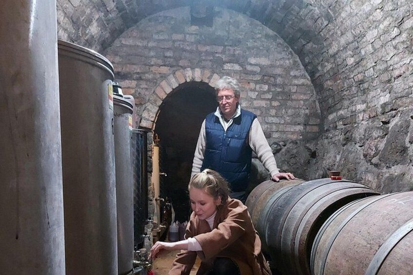 A person working with a large metal barrel in a brick building with arched ceilings. 4