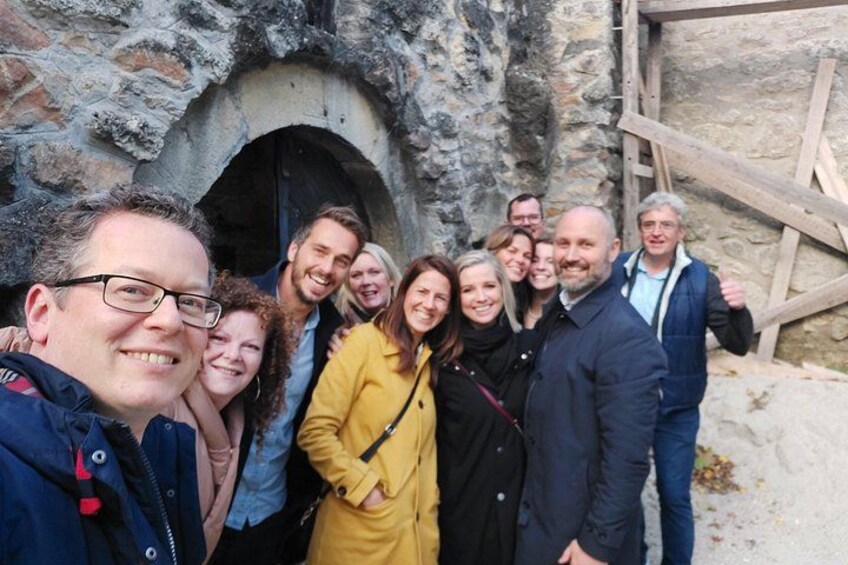 A group of people standing in front of a stone structure with a wooden ladder. 1