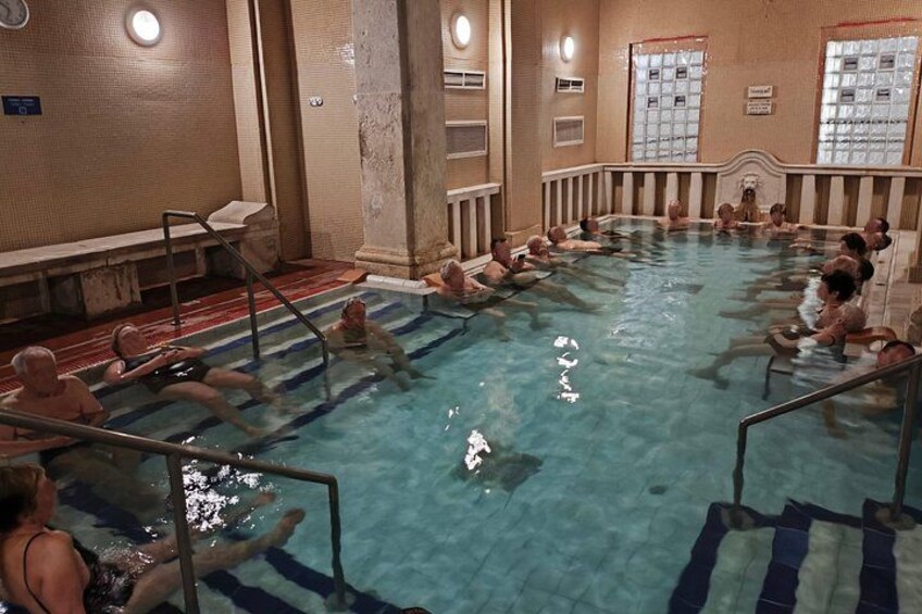 Ein Schwimmbecken mit Menschen im Wasser und am Beckenrand. 4