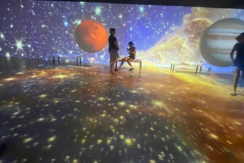 A space-themed exhibit with a large planet and stars projected on the ceiling. 2