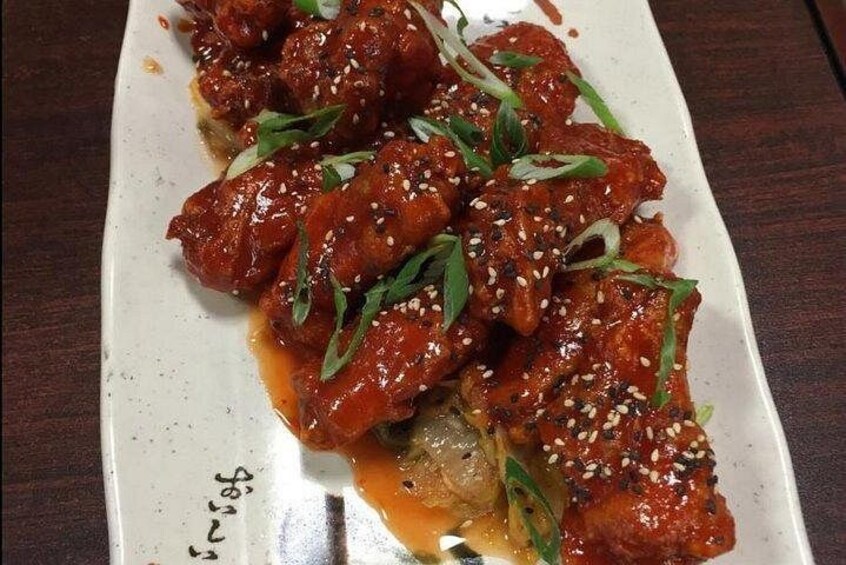 A dish of glazed chicken wings garnished with sesame seeds and green onions. 3