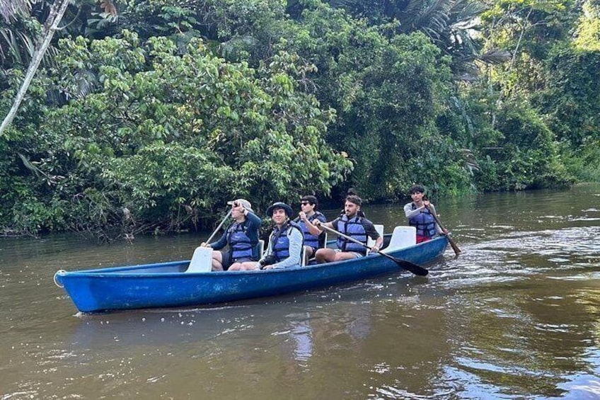 A group of people in a blue canoe on a river surrounded by dense greenery. 3
