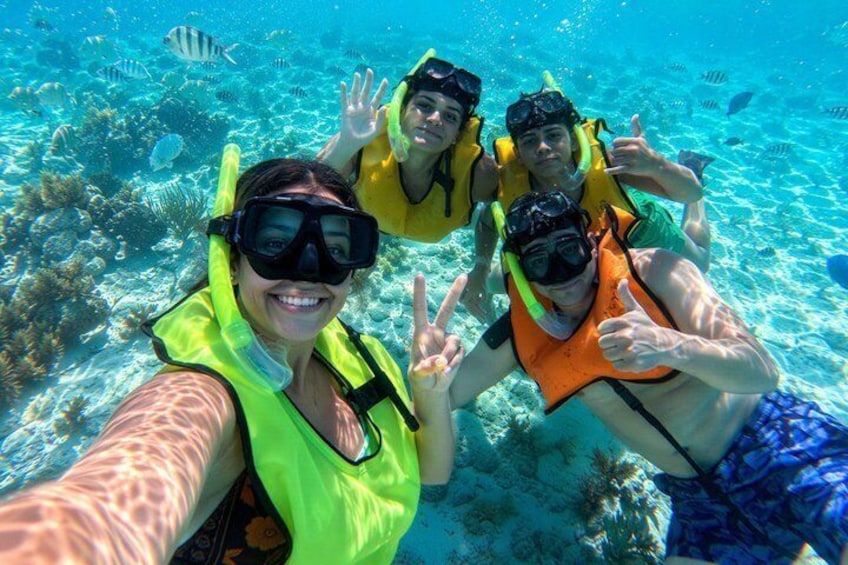 Three people scuba diving underwater with coral reefs and fish in the background. 1
