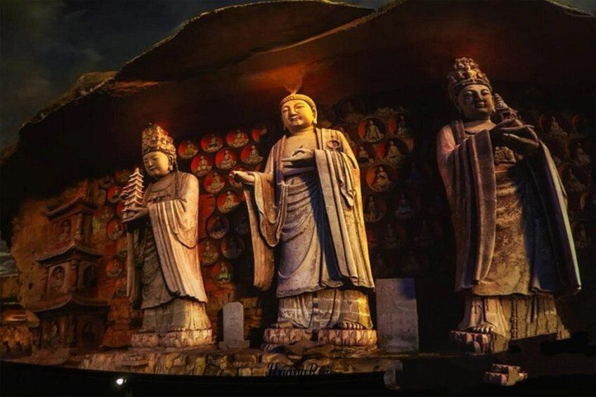 Drie grote stenen beelden in een tempel, met ingewikkelde gravures op de achtergrond. 5