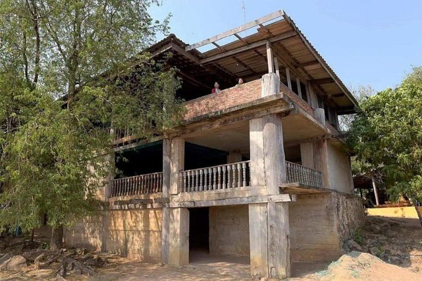 A two-story building under construction with a balcony, surrounded by trees. 5