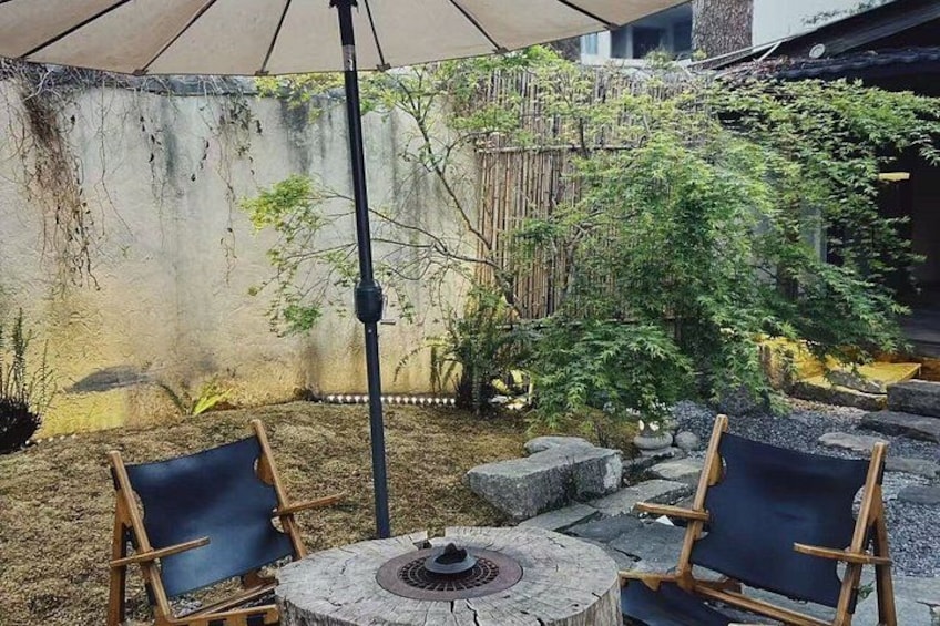 Eine Terrasse mit zwei Holzstühlen, einem Tisch und einem Bambuszaun. 4