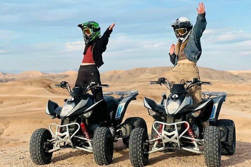 Two people on quad bikes in a desert landscape. 1