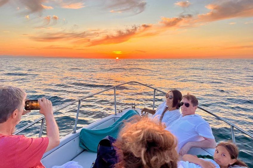 A sunset over the ocean with a boat and people on it. 4