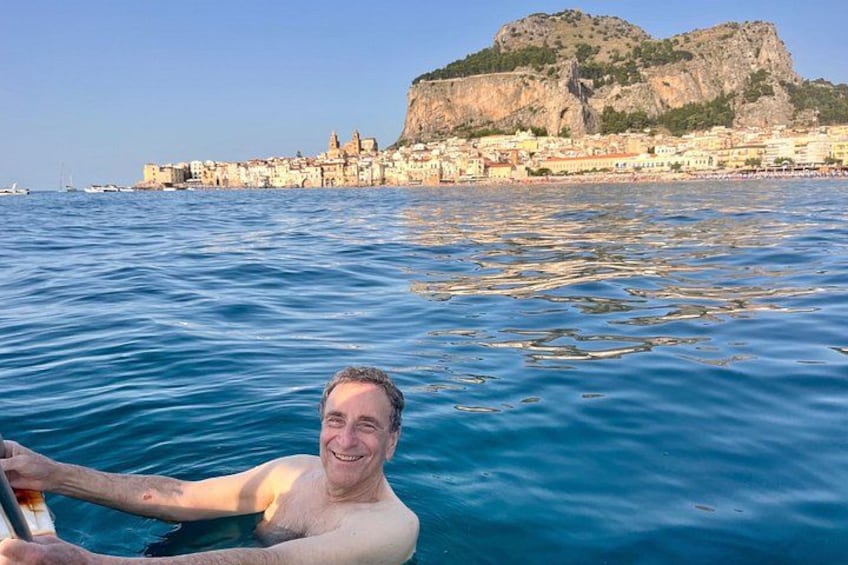 A person in the water with a cityscape and a hill in the background. 5