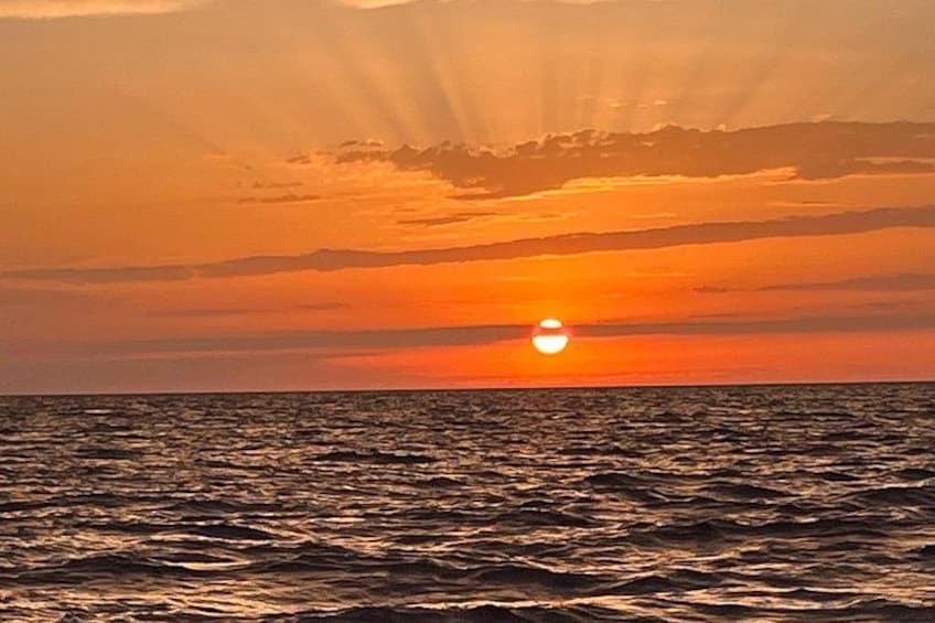 A sunset over the ocean with the sun partially visible on the horizon. 2