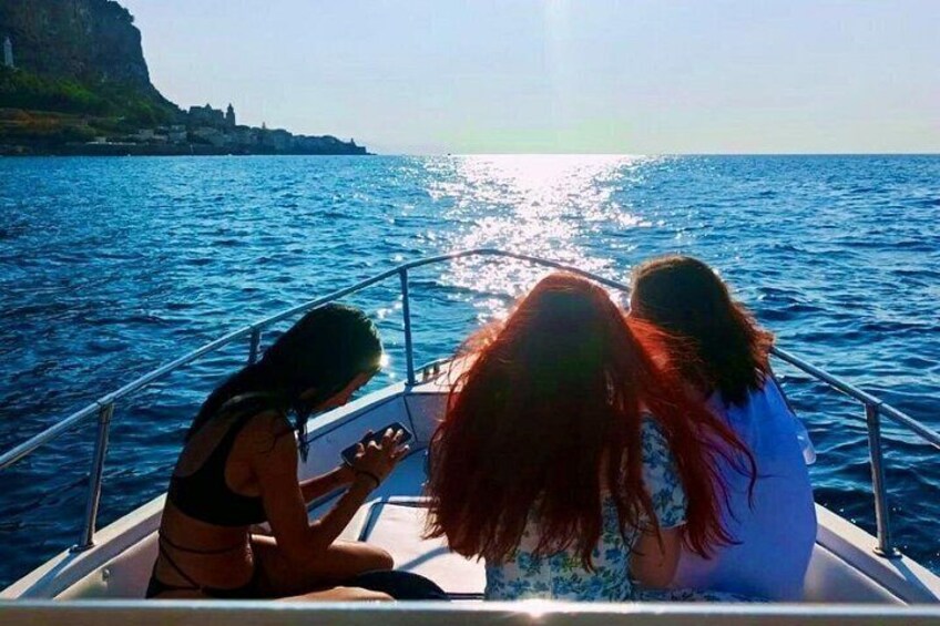 Drei Personen in einem Boot vor einer Küstenlinie. 2