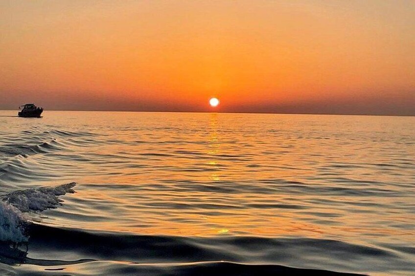 A sunset over calm ocean waters with a boat in the distance. 3