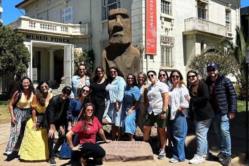 A group of people posing in front of a building labeled 'Museo Fonck' with a large stone sculpture in the background. 3