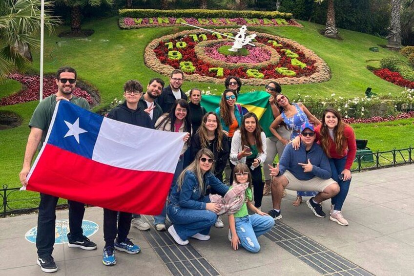 Un groupe de personnes posant dans un jardin, avec une composition florale circulaire et un drapeau. 3