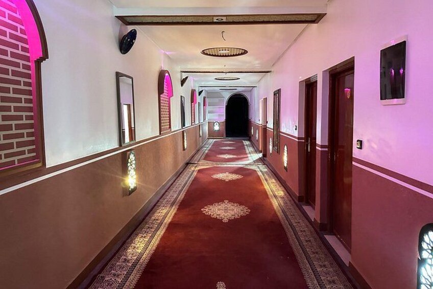 A long hallway with a red carpet, arched doorways, and wall sconces. 4