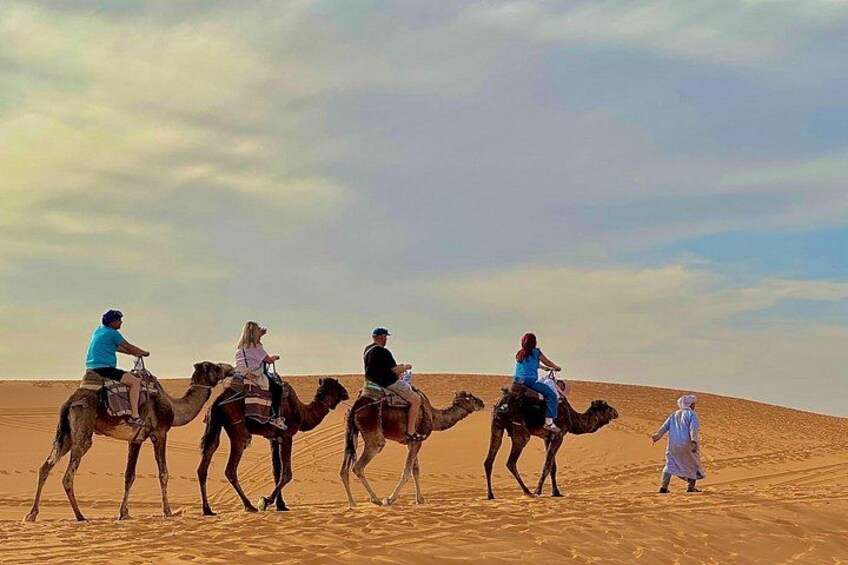 A group of people riding camels across a desert landscape. 1