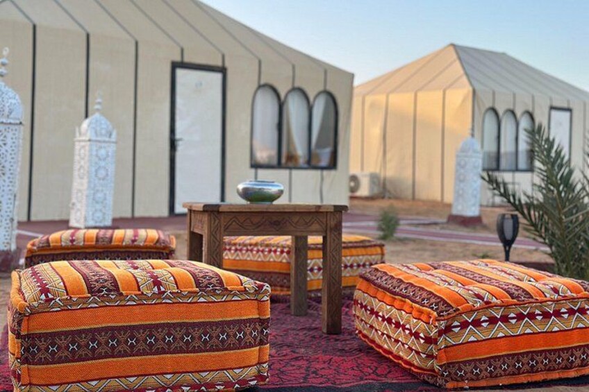 A traditional Moroccan courtyard with ornate cushions, a wooden table, and a tent-like structure. 3