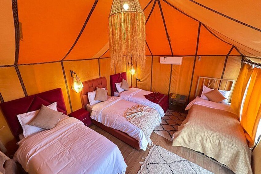 A tent with three beds, each with a headboard and pillows. 2