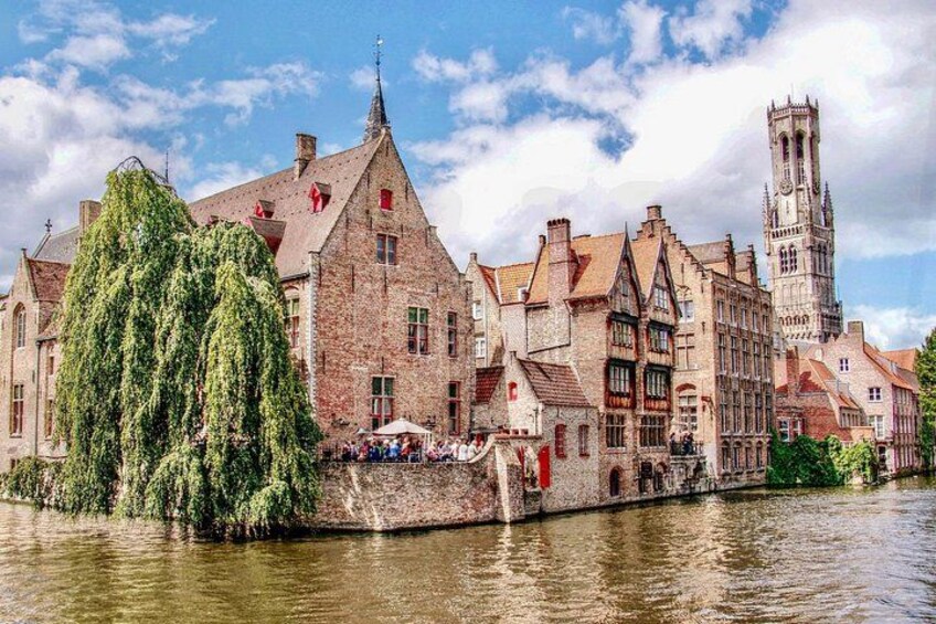 A historic town with a river, traditional buildings, and a prominent church tower. 1