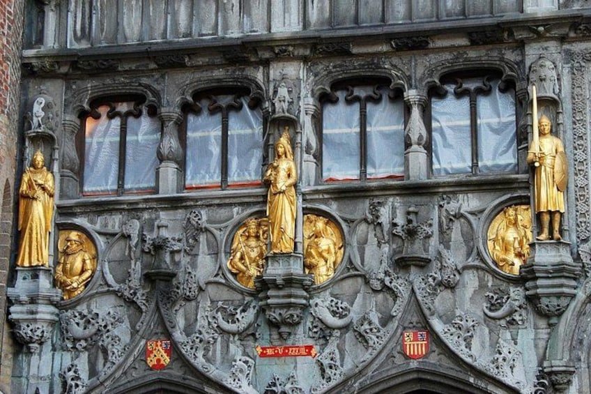 A building facade with ornate stone carvings, statues, and heraldic shields. 5