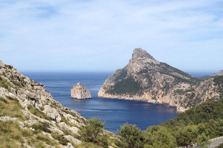 A mountainous landscape with a prominent peak, a rocky coastline, and a clear blue sea. 4