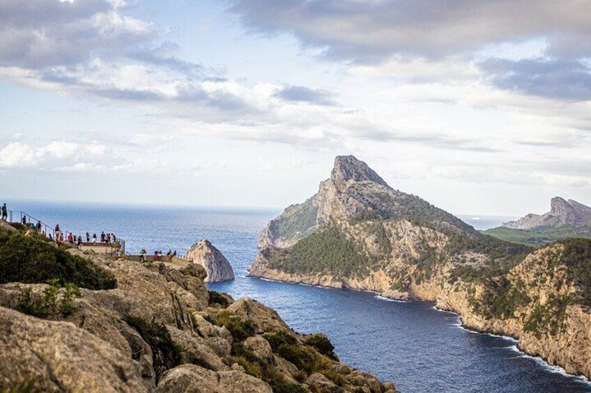 A coastal landscape with rocky cliffs, a prominent mountain peak, and a clear view of the sea. 5
