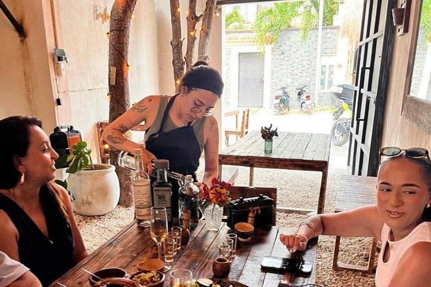 Une table en bois avec des bouteilles, des verres et une personne en train de verser une boisson. 2