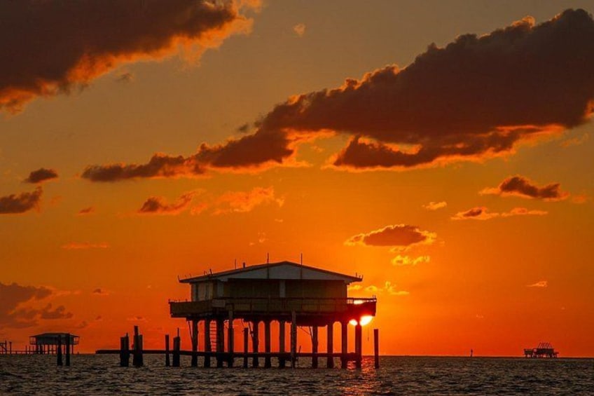 A pier extending into the water with a building on top, under a sunset sky. 5