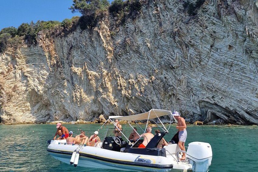 A boat with people on a rocky coastline. 3