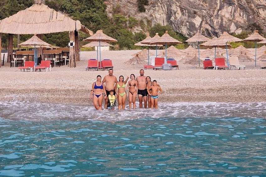 A family standing in shallow water at a beach with umbrellas and lounge chairs. 5