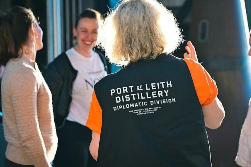 En person som bär en väst med texten ”Port of Leith Distillery Diplomatic Division”. 1