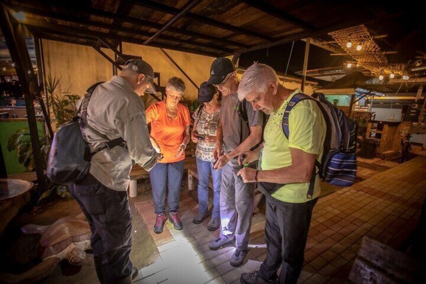 Un gruppo di persone in un ambiente interno rustico e scarsamente illuminato, con travi in legno e lampade a sospensione. 1