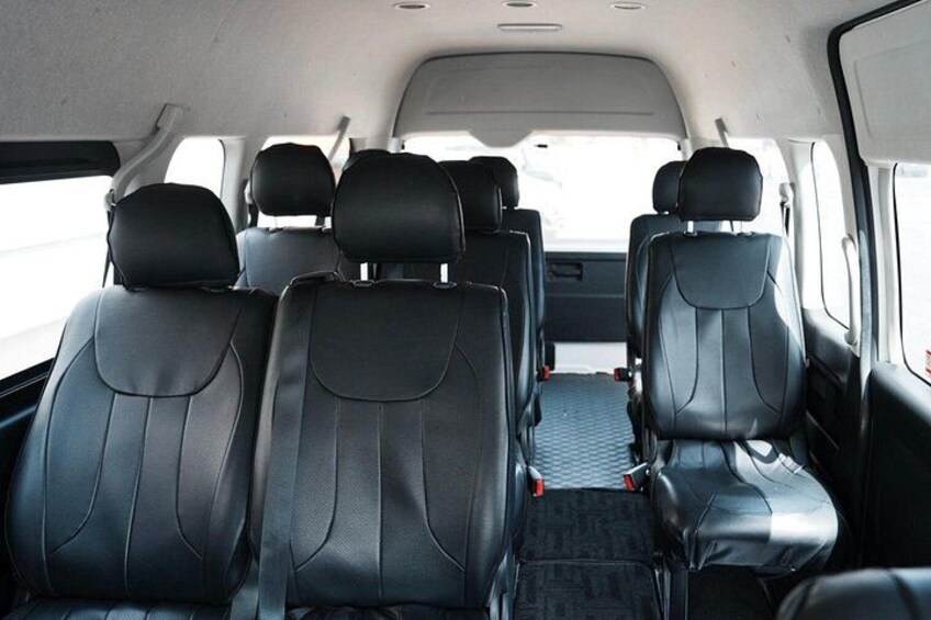 A vehicle interior with black leather seats and a central aisle. 3