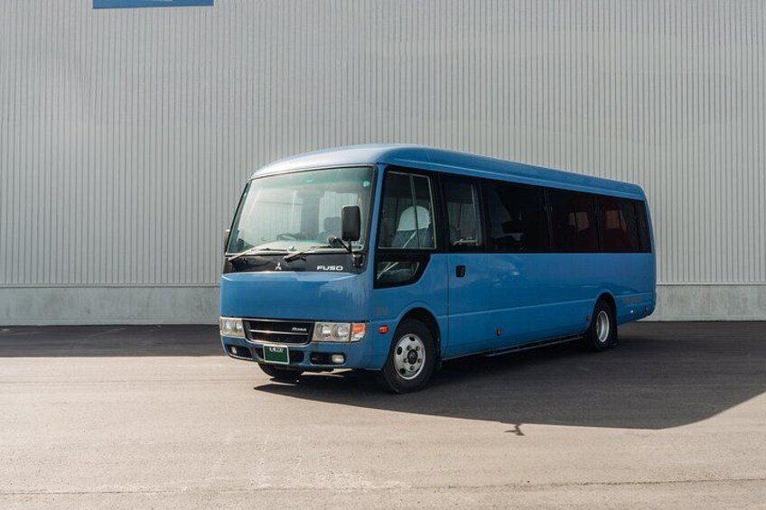 A blue bus parked in front of a white building. 2