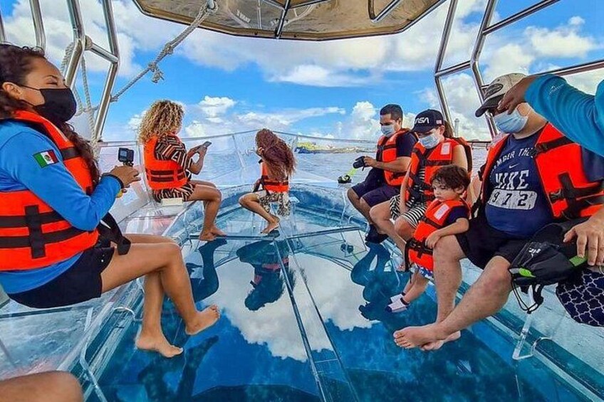 A group of people on a boat wearing life jackets, with clear skies and calm waters. 1