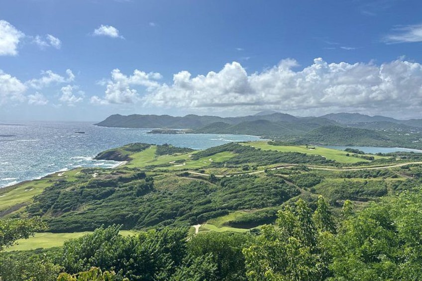 Paesaggio costiero con colline verdi, una spiaggia e cielo sereno. 2