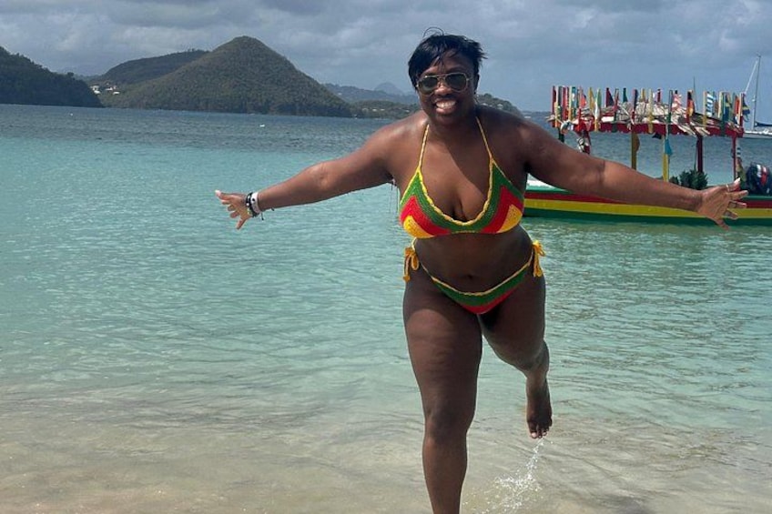 Una persona in bikini colorato in acque basse, con una barca e delle bandiere sullo sfondo. 5