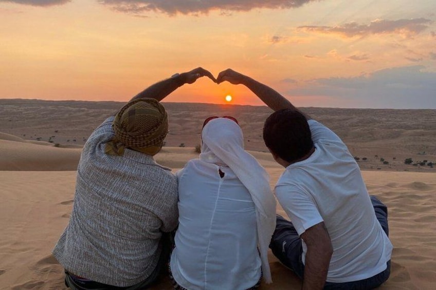 Tres personas sentadas sobre dunas de arena al atardecer. 2