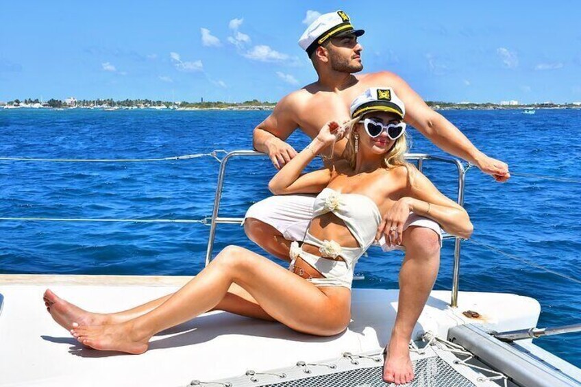 A couple on a boat with a clear blue sea and distant land in the background. 1