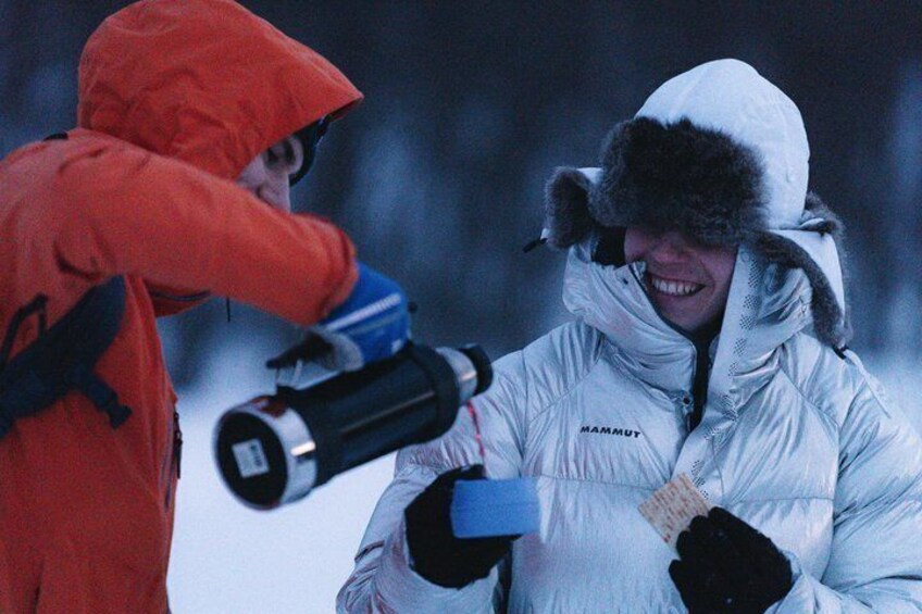 Two people in winter clothing, one in red and one in white, with a large telescope. 5