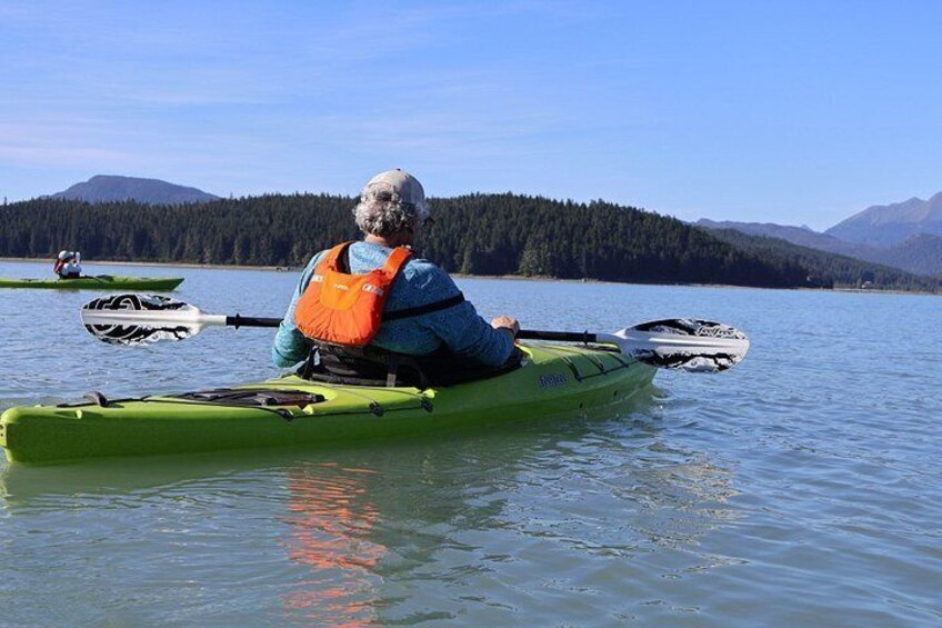 Una persona fa kayak su un lago calmo, con montagne sullo sfondo. 4