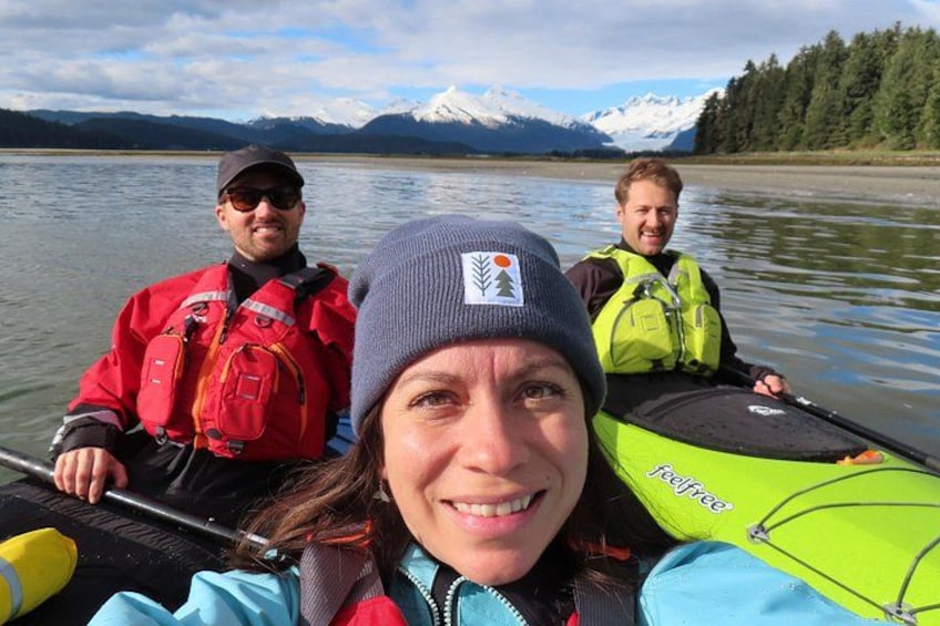 Tre persone su un kayak, con un lago e montagne sullo sfondo. 2