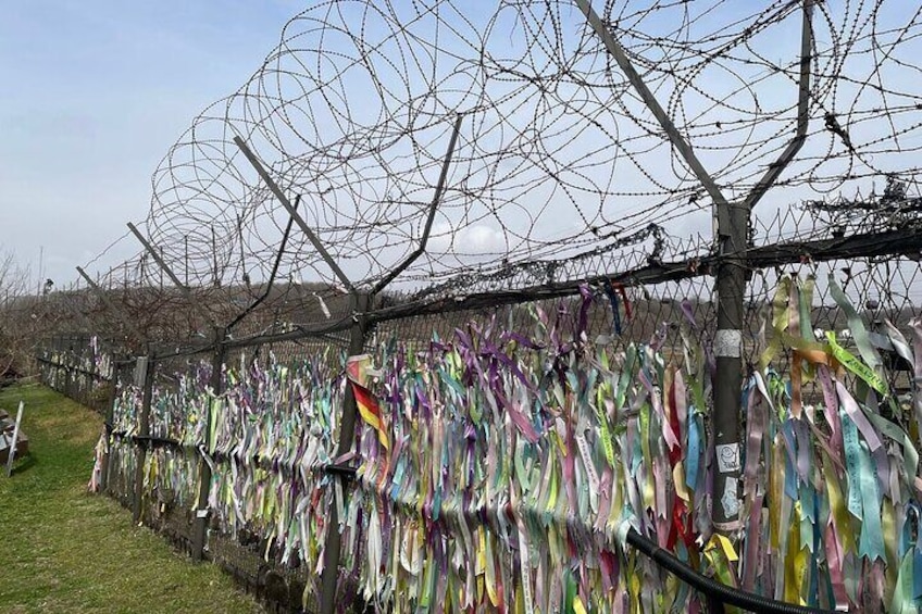 A fence with colorful ribbons attached to it. 3
