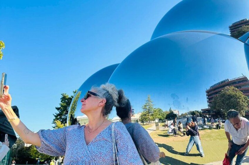 Una persona tomándose un selfie frente a una gran estructura en forma de cúpula azul. 4